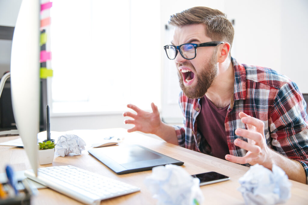 Mad agressive man designer looking at monitor and shouting