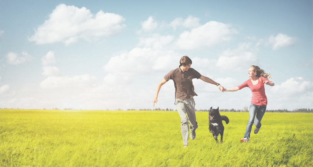 Couple and Dog Running Happily in Field